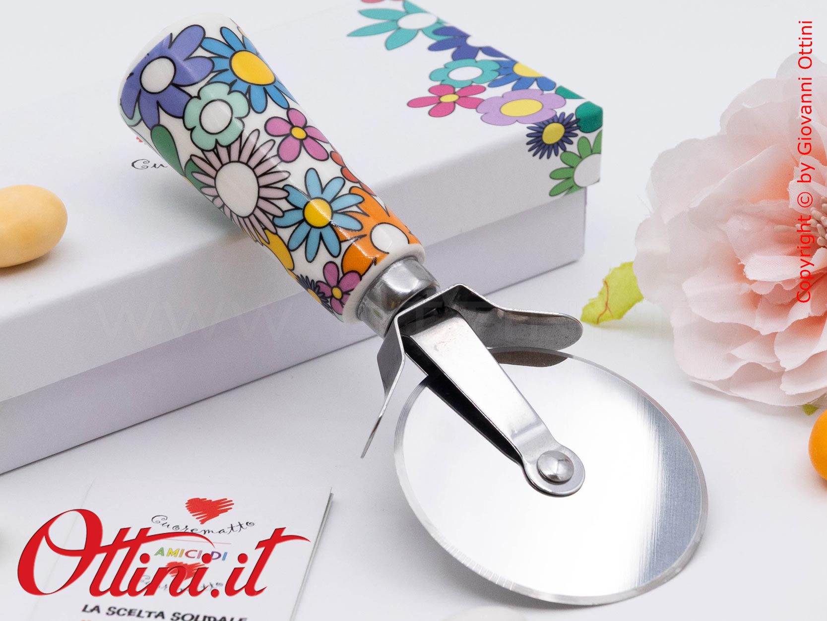 DA202 - il Tagliapizza Fiorello di Cuorematto è una bomboniera solidale utile a tavola, caratterizzato da colori floreali vivaci e un design esclusivo