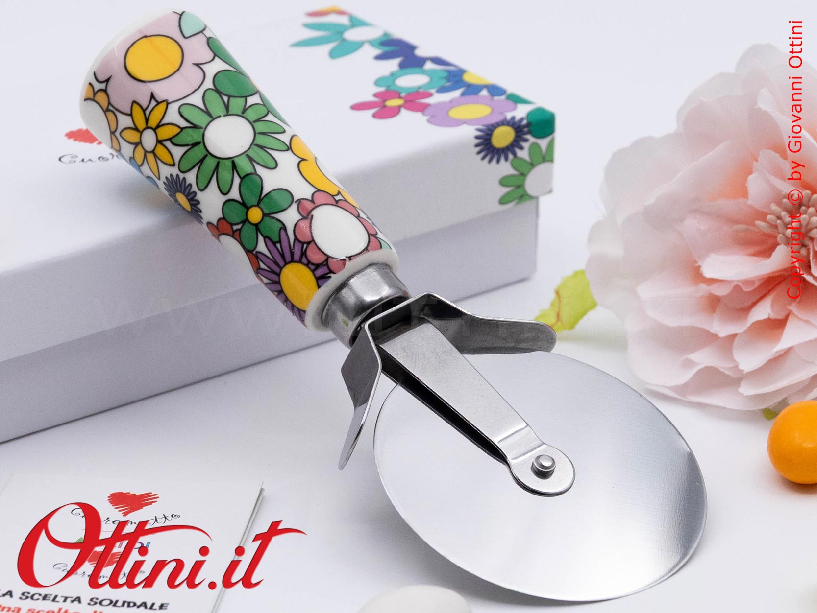DA202 - il Tagliapizza Fiorello di Cuorematto è una bomboniera solidale utile a tavola, caratterizzato da colori floreali vivaci e un design esclusivo