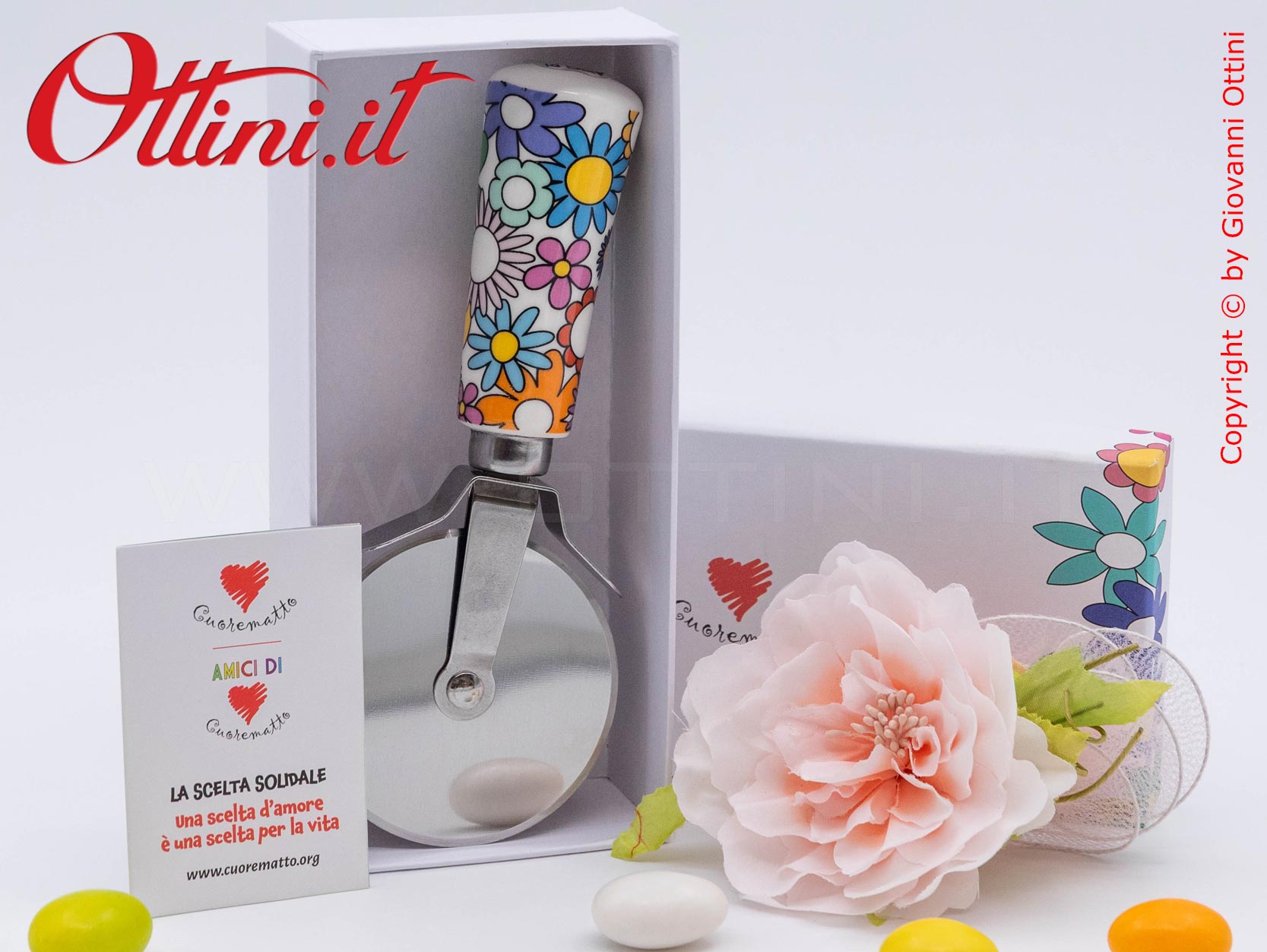 DA202 - il Tagliapizza Fiorello di Cuorematto è una bomboniera solidale utile a tavola, caratterizzato da colori floreali vivaci e un design esclusivo