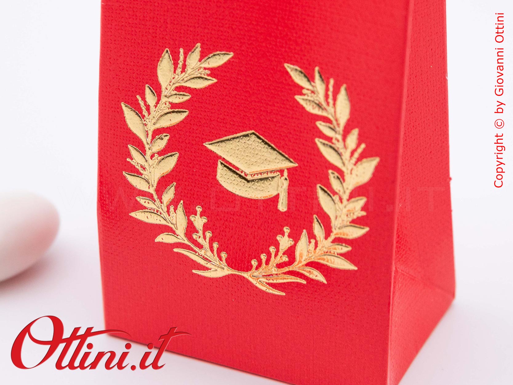 Questa Scatolina porta confetti per la Laurea è realizzata in cartoncino rosso con finitura effetto tela e una stampa di una corona di alloro con il Tocco